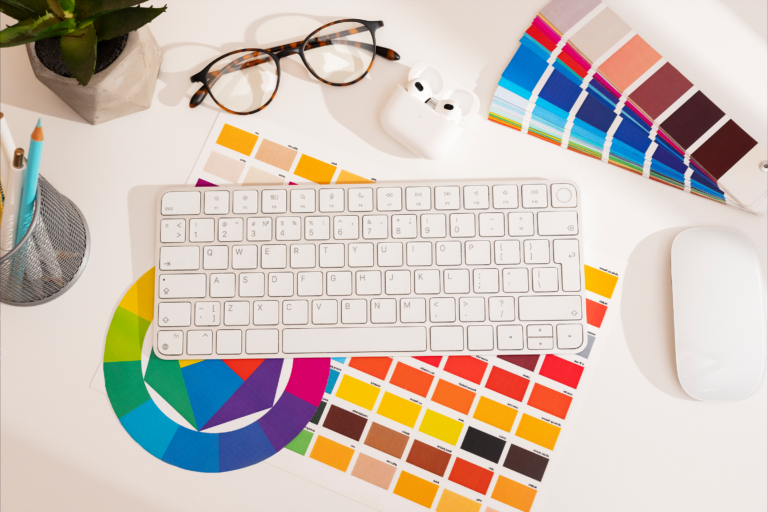 Teclado blanco de ordenador sobre muestras de pantoneras y círculo cromático para representar el sistema visual para marcas digitales.