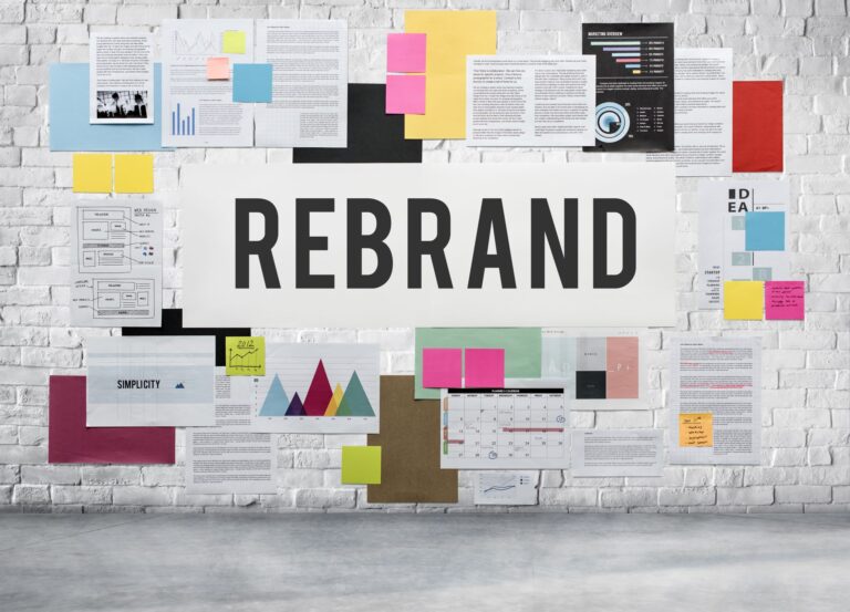 Rediseño de identidad corporativa: pared con la palabra REBRAND rodeada de bocetos, gráficos y notas de colores